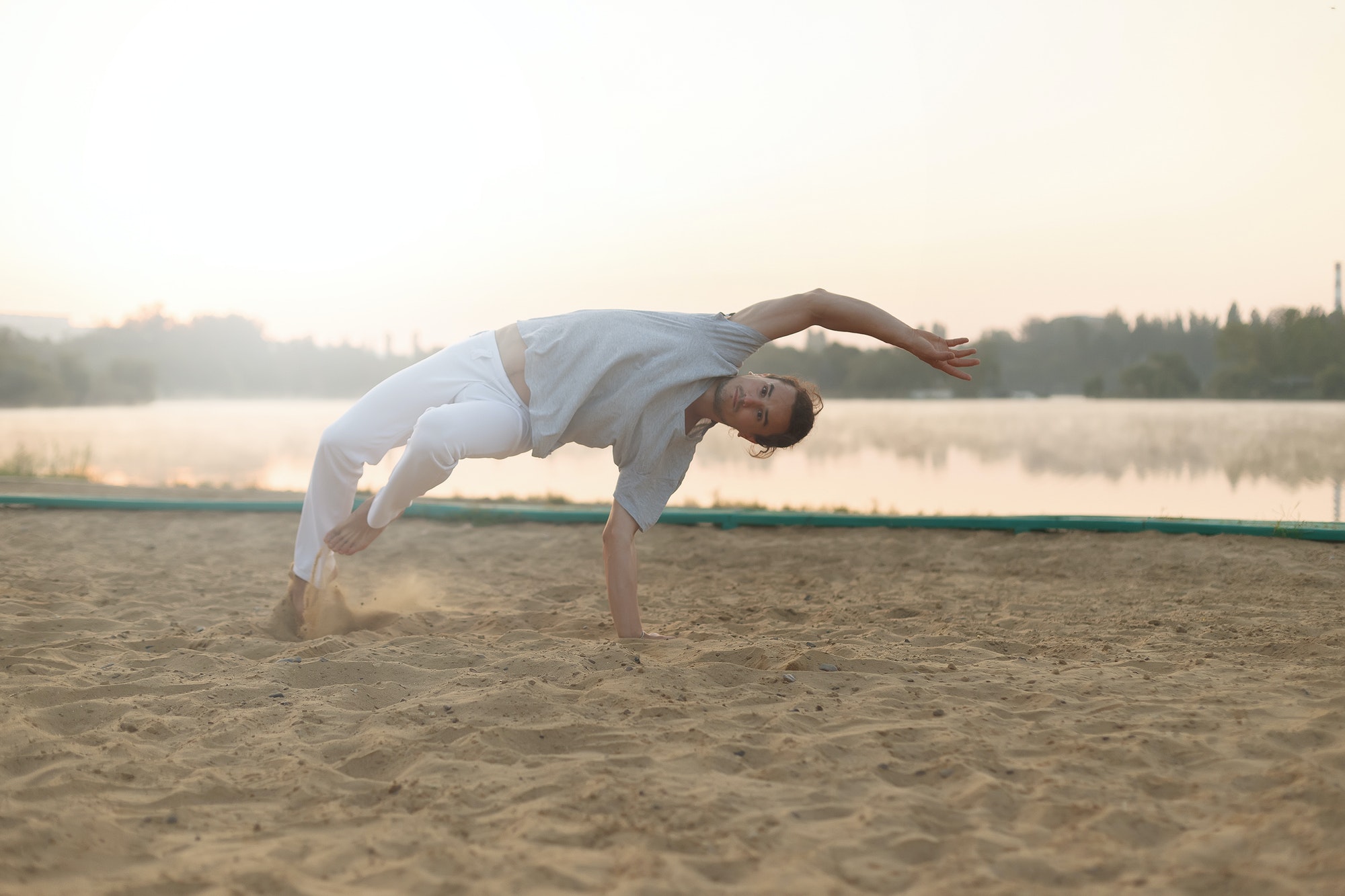 Athletic capoeira performer workout training on the beach sunris